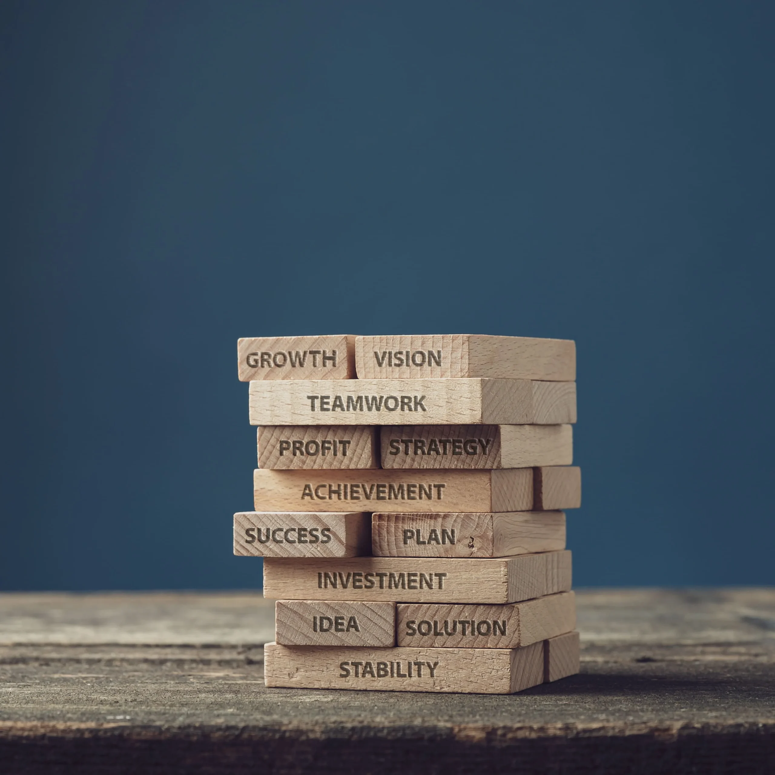 Stack of wooden blocks engraved with words like growth, vision, teamwork, strategy, achievement, and stability, representing Hydrolyz’s mission of advancing sustainable electrochemical solutions for metal recovery and wastewater treatment.